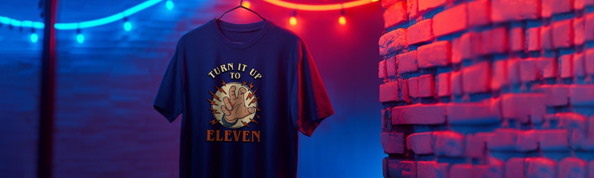 Navy t-shirt with "Turn It Up To Eleven" a funny mix between Stranger Things and Spinal Tap. T-shirt on a hanger against a colorful brick wall.